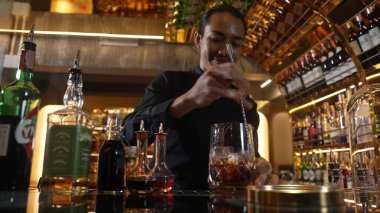 Zeki Asyalı barmen bardakta karıştırılmış alkol şurubunu buzla karıştırıyor. Çünkü kayanın üzerinde kamera var. Gece kulübünde taze kokteyl kokteylleri karıştırıyor. Vinosity.