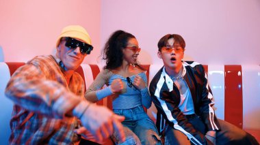 Mutlu kız kameraya bakıyor ve kanepede otururken pop müzik dinliyor. İspanyol kadın serbest stil dans ederken kameraya bakıyor neon ışıkta çeşitli arkadaşlarla dans ediyor. Mutluluk.