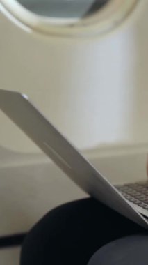 Genç iş adamı uçakta dizüstü bilgisayar kullanıyor. İş seyahati konsepti .