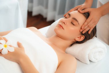 Kafkasyalı kadın stres önleyici kafa masajından ve lüks tatil beldesi ya da otel spa salonundaki modern ışık ortamında yüz güzelliği eğlencelerini şımartmaktan hoşlanıyor. Sessiz.
