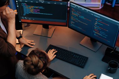 Akıllı web sitesi geliştirme kodlayıcı sistemi ile tartışan IT geliştiricilerinin üst görüşü modern ofisteki neon ışık odasında iki ekran bilgi teknolojisini çevrimiçi çalıştırıyor. İnfobahn.