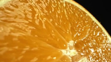 Portakal diliminin bir makrografi görüntüsü, parlak, izole edilmiş bir arkaplan üzerine yerleştirilmiş, narenciye cazibesinin görsel bir başyapıtı olarak gözler önüne seriliyor. Siyah arkaplanlı bir dilim portakal. Geliştirilebilir.