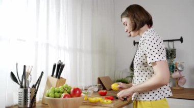 Çekici beyaz anne salata yapmak için taze sebze doğruyor. Mutlu enerjik akıllı anne kahvaltıda sağlıklı yemek pişirirken modern mutfakta çalışıyor. Yemek hazırlama konsepti. Pedagoji.