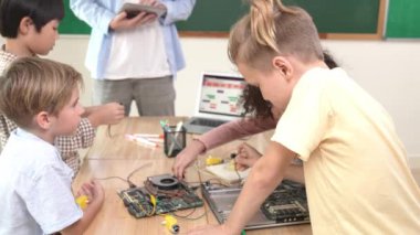 Öğretmenler tablet verileri analiz ederken sevimli enerjik çocuklar elektronik panoda çalışıyor. Çeşitli öğrenci grubu ana tahtayı tamir ediyor ve yapay zeka ve programlama sistemini öğreniyor. Pedagoji.