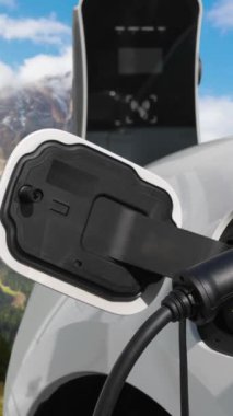 Temiz çevre için temiz enerjinin yol açtığı ilerici elektrikli araba kavramının arka planı olarak dağın tepesinde bulutun zaman kavramının yer aldığı doğal manzara. EV araba şarj istasyonunda şarj oluyor..