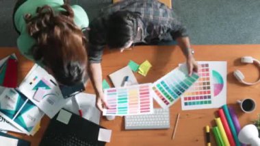 Akıllı tasarımcının renkli paletlerden renk seçmesine yardım ederken yukarıdan aşağı görünümü. Dizüstü bilgisayardan logoya bakarken birlikte çalışan ve planlayan iş adamlarının hava görüntüsü. Sempozyum.