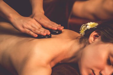 Sıcak mum ışığı olan lüks bir tatil köyündeki kaplıca salonunda sıcak taş masajı yapan mutlu çift, bazalt taşı masajının keyfini çıkarırken rahatlatıcı bir sıcaklıkla vücudun üzerinde süzülüyor. Sessiz.