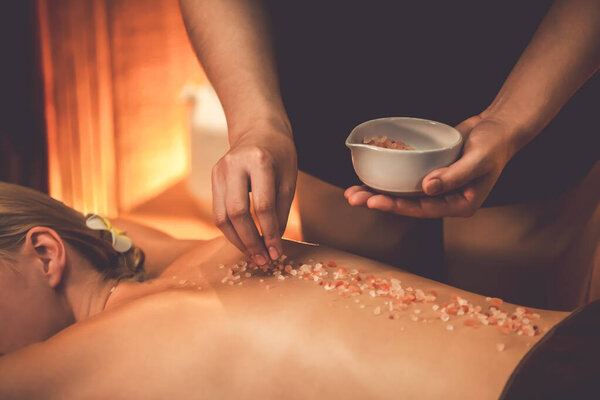 Женщина-клиент, проводящая пилинг в роскошном спа-салоне с теплым свечой окружающей среды. Косметическое лечение бальзамическим скрабом в Health spa scrub. Quiescent