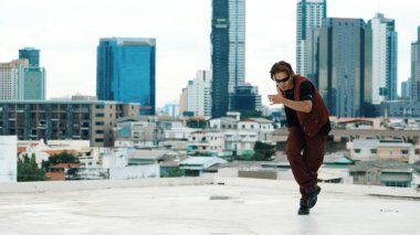 Profesyonel Asyalı break dansçı B çocuk dansı yaparken çatıda çok kültürlü arkadaşlar var. Genç modern dans grubu hip hop hareketi yapıyor. Tarz, moda, aksiyon. Açık hava sporu 2024. Hiphop.