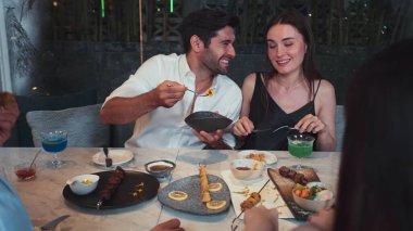 Grup arkadaşı ya da çift, ızgarada ve ana yemek masasında yemek yerken akıllı telefonla konuşuyor. Lüks restoranda etkileyici bir dostluk ortamında tanışma teması. Vinosity.