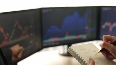 Borsa pazarlama şirketindeki iş yatırımcıları, zarar için mum bar fiyatlarını analiz eden monitörlere bakarak hisse senedi pazarlamasını not alıyor ve analiz ediyor. Filizlenen