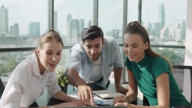 Profesyonel iş ekibi başarılarını kutlarken dizüstü bilgisayar kullanarak iyi haberler alıyor. Müdür, modern ofisteki meslektaşıyla el çırparken dizüstü bilgisayarı işaret ediyor. İzleme