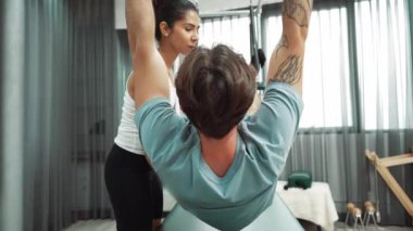 Eğitmen rehberliğinde Pilates Cadillac 'ta ters bacak yükseltme pratiği yapan sağlıklı bir müşteri. Çekirdek dayanıklılığını ve üst vücut dengesini arttırmak için Cadillac 'ı geren adam. Alışkanlık.