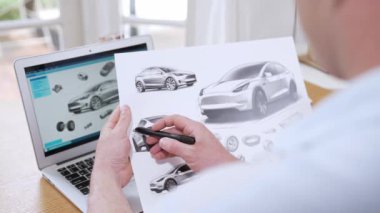 Araba tasarım mühendisi otomobil işi için otomobil prototipini ev ofisinde analiz ediyor. Otomotiv mühendisliği tasarımcısı dikkatle analiz eder, kusurları bulur ve dizüstü bilgisayarla araba tasarımında gelişmeler kaydeder.