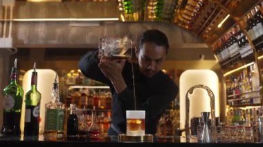 Asyalı barmen soğuk bardağa karışık viski dökerek soğutmalı buzlu içecek üretiyor. Lüks ılık barlarda alkol yenileme gösterisine odaklanan yaratıcı bir reklam yapıyor. Vinosity.