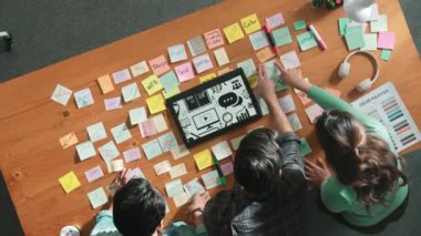 Toplantı masasında renk paletleriyle birlikte yapışkan notlar kullanarak yaratıcı tasarımcının beyin fırtınası fikrinin üst görüntüsü. Akıllı takımın hava görüntüsü tabletten simge grafiği seçiyor. Sempozyum.