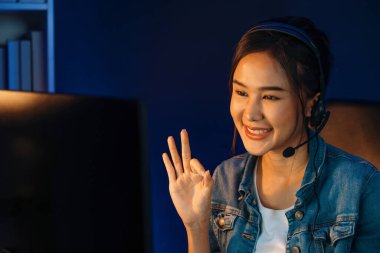 Sunucu kanalı Asyalı etkileyicisi canlı yayında konuşuyor. Sosyal medyada kulaklık takıyor, bilgisayar kaydı yapıyor, dinleyicileri selamlıyor ve Neon Modern Stüdyoları 'nda online olarak koçluk yapıyor. Taktik.