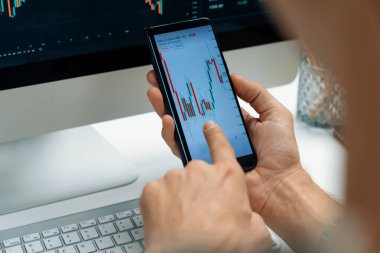 Akıllı borsa yatırımcıları ekranda akıllı telefon ile piyasa borsasını işaret ederek dizüstü bilgisayarın yanı sıra en yüksek dinamik yatırım oranını göstererek, modern işyerindeki veri planlamasına odaklanıyorlar. Bireysel.