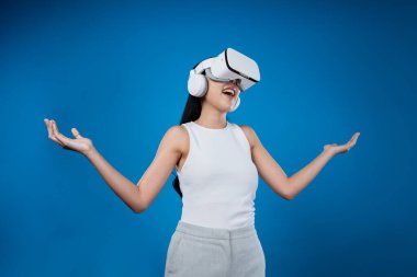 Mavi arka planı olan zeki bir kadın metaevrene bağlı VR kulaklık takıyor, gelecekçi siber uzay topluluğu teknolojisi. Zarif bir kadın sanal bir manzara gördüğü için heyecanlı. Halüsinasyon.