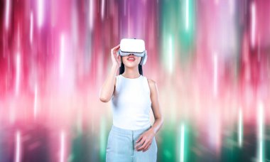 Beyaz VR kulaklık takan bir kadın ve beyaz kolsuz bağlantı metaverse, gelecekteki teknoloji siber uzay topluluğu yaratıyor. Etrafında soyut bir ışık görmek hoşuna gidiyor. Halüsinasyon.