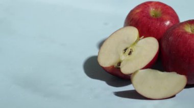Mavi arka planda dilimlenmiş kırmızı elmaları kapatın. Elma dilimlenmiş makarnanın mavi arka planında elmacı ve suyun dökülmesi ve el sallaması. Sağlıklı beslenme ve taze üretim kavramı. Pabulum.