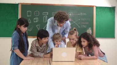 Kafkas öğretmeni ve çeşitli öğrenciler sınıfta dizüstü bilgisayara bakıyor. Kodlama programını öğrenen ya da öğretmenlik yaparken yazılım kullanarak oluşturulan çok kültürlü çocuklar. Pedagoji.