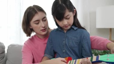 Kafkasyalı bir anne evde akustik müzik öğretirken ukulele çalan mutlu kız. Sevimli çocuk enstrüman öğreniyor. Kafkasyalı mutlu anne ve kız birlikte vakit geçiriyorlar. Pedagoji.