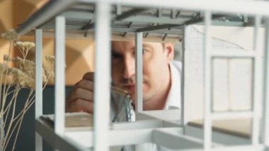 Kafkasyalı mimar mühendisinin yakın çekimi ev inşaatını denetlemek ve bina malzemelerini kontrol etmek. Proje yöneticisi modele dikkatlice bakarken kalemi işaret ediyor. Yönlendirici.