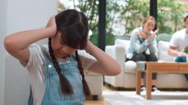 Stresli ve mutsuz genç kız köşeye kıvrılıp kulaklarını kapatarak arka planda ebeveyninin tartışmasını engelliyor. Evde aile içi şiddet ve travmatik çocukluk depresyona dönüşür. Titiz