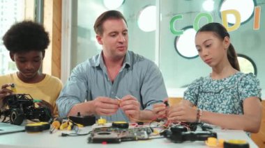 Yetenekli öğretmen Afrikalı çocuğa elektrikli aletleri açıklarken liseli kız model tamir ediyor. Çok kültürlü bir öğrenci robot araba yapımı ve elektronik aletleri öğreniyor. Öğretim