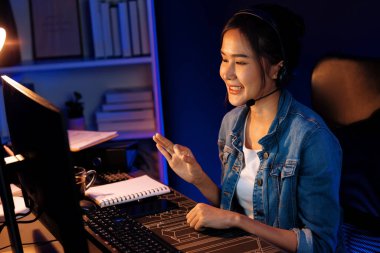 Sunucu kanalı Asyalı etkileyicisi canlı yayında konuşuyor. Sosyal medyada kulaklık takıyor, bilgisayar kaydı yapıyor, dinleyicileri selamlıyor ve Neon Modern Stüdyoları 'nda online olarak koçluk yapıyor. Taktik.