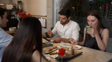 Grup arkadaşı ya da çift, ızgarada ve ana yemek masasında yemek yerken akıllı telefonla konuşuyor. Lüks restoranda etkileyici bir dostluk ortamında tanışma teması. Vinosity.