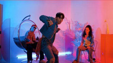 Çok kültürlü bir arkadaş kürsüde otururken Asyalı yetenekli bir dansçı modern müziğe geçiyor. Profesyonel dansçı, hipster takımı tezahürat yaparken ve desteklerken enerjik adımlar atıyor. Mutluluk.