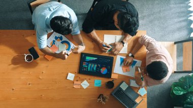 Yönetici, toplantı odasındaki meslektaşlarına mali grafiği açıklar. Farklı pazarlama ekibinin tabletle masada otururken fikir ve planlama stratejisini en üst düzeyde paylaşması. Cemaat.