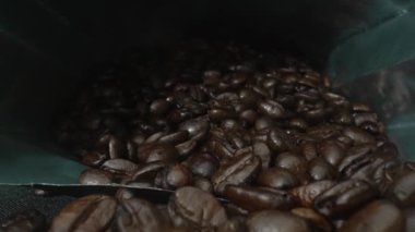Kavrulmuş kahve çekirdekleri toplanıyor ve ayrı siyah arka planda dağılıyor. Kapatın ya da kahve yapmak için paketlenmiş kahve çekirdeğini hazırlayın. Yakınlaştır. Kafein. Pabulum.