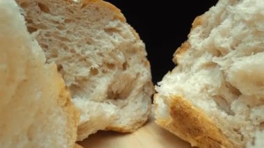 Koyu arkaplanda yırtık taze ekmek parçalarını yakın plan çek. Tahta tepsiye konmuş Fres ekmeklerinin makro fotoğrafları. Yakınlaştır ve kamera hareketini döndür. Gurme ve fırın konsepti. Pabulum.