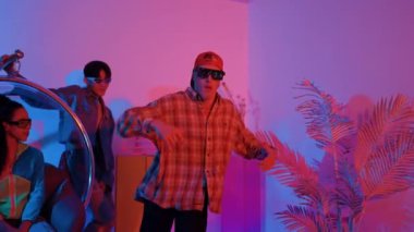 Stüdyoda gündelik kıyafetleri olan çok kültürlü bir arkadaş tezahürat yaparken mutlu hipster break dansları. Profesyonel sokak dansçısı hip hop ritmi ya da neon veya kurşun ışıkla kafiyeli bir şarkı söyler. Mutluluk.