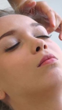 Lüks bir spa merkezinde masaj terapisti tarafından yüz masajı ve spa tedavisi için kaplıcaya uzanmış rahat bir kadın. Sağlık, stres atma ve gençleştirme kavramı.