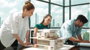 Beyaz proje yöneticisi dizüstü bilgisayar analiz verilerini kullanırken, mimar mühendis ekibi ev modeli inşaatını analiz etmek için birlikte çalışıyor. Bir grup tasarımcı ev tasarımı hakkında konuşuyor. İzleme