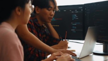 Yavaş çekim arkası yazılım geliştirici mühendisi bilgisayar programlama için birlikte çalışarak hata ayıklama kodunu çözüyor, ofiste monitörde karmaşık algoritmaları çözüyor. Filizlenen