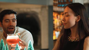 Süslü çam neon karlı bir gece kulübünde süslü püslü çam ağacından konuşan ve kokteyl içen gülümseyen bir kadın. Vinosity.