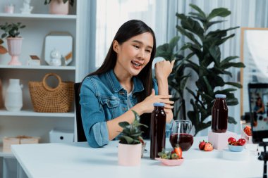 Gülümseyen, güzel Asyalı genç, lezzetli karışık çilek ve kiraz suyu detoksu içeceklerini inceleyen, sosyal medyada özel promosyon satışı için sağlıklı ürünler sergileyen. Taktik.