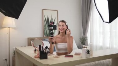Sosyal medya için güzellik ve kozmetik video içeriği hazırlayan genç bir kadın. Güzellik blogcusu kameraya gülümserken seyircilere ve takipçilere güzellik bakımını gösteriyor. Düzenle