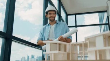 Gökdelen manzarasına bakarken yürüyen profesyonel mimar mühendisi. Masaya yerleştirilmiş ev modeliyle pencereye bakarken yetenekli proje yöneticisi proje planını tutuyor. Tasarım. İzleme