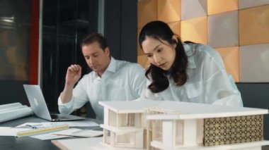 Bir grup mimar mühendis birlikte çalışıyor ve ofis tasarımı hakkında tartışıyorlar. Genç mühendis ev modelini ölçerken yönetici dizüstü bilgisayar kullanıyor. İş tasarımı konsepti. Yönlendirici.
