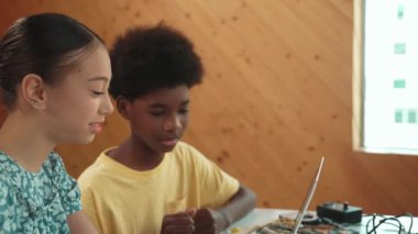 Afrika 'lı bir erkek ve beyaz bir kızın günlük giysiler içinde BTMM teknoloji sınıfında dizüstü bilgisayar ve elektronik ekipmanlarla kod yazma ya da programlama sisteminde birlikte çalıştıklarını gösteren site görüntüsü. Öğretim