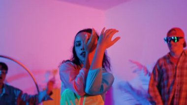 İspanyol hipster renkli kıyafetler giyer ve serbest stil müziğe el sallar. Profesyonel break dansçı neon ışıklarıyla ve modern stüdyo arkadaşlarıyla coşkuyla dans ediyor. Mutluluk.