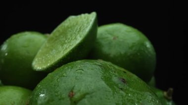 Limon dilimleri titizlikle bir yığın halinde, siyah arkaplana göre dizilmiş. Her bir kireç dilimi çarpıcı detaylar, canlı yeşil rengi ve baştan çıkarıcı dokusu ile yakalanır. Kapatın. Geliştirilebilir.
