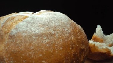 Koyu arkaplanda yırtık taze ekmek parçalarını yakın plan çek. Tahta tepsiye konmuş Fres ekmeklerinin makro fotoğrafları. Yakınlaştır ve kamera hareketini döndür. Gurme ve fırın konsepti. Pabulum.