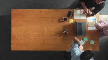 Akıllı iş adamlarının el çırparken dizüstü bilgisayara baktığı ve başarılı bir projeyi kutlamak ya da toplantıdaki satışları artırmak için beşlik çaktığı en tepeden aşağı hava görüntüsü. Cemaat.